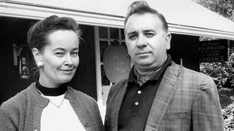 Black and white photo of a man and woman standing in front of a house.